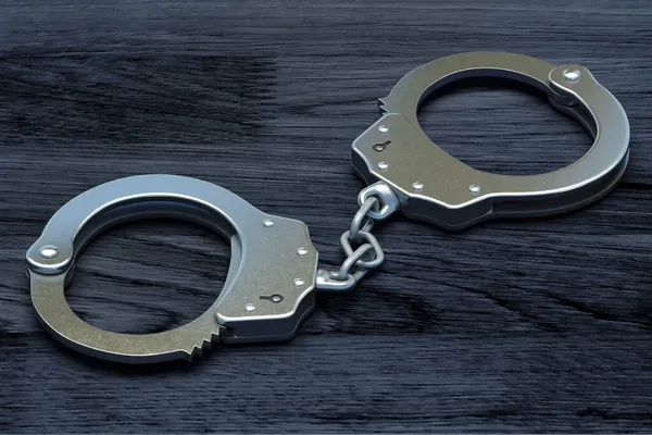 Police metal handcuffs on dark wooden background. — Stock Photo, Image