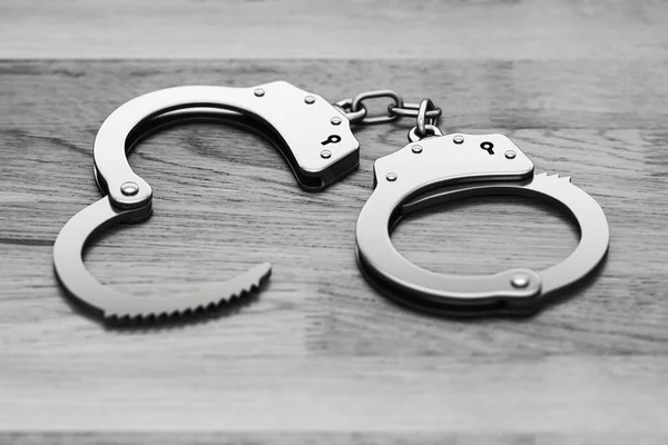 Police metal handcuffs on wooden floor. — Stockfoto