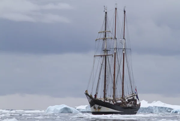 Kleines Segelschiff in antarktischen Gewässern zwischen Eisschollen und Eis — Stockfoto