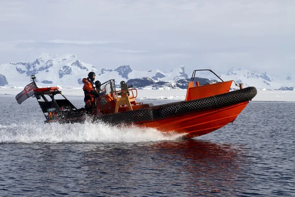 Bateau orange naviguant à grande vitesse dans les eaux antarctiques contre mo — Photo