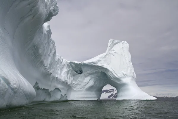 Grand iceberg avec un arc traversant dans les eaux antarctiques — Photo