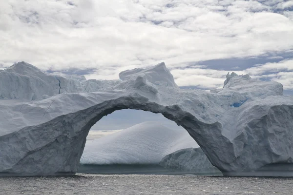 Grote door-arch in een ijsberg op een bewolkte dag — Stockfoto