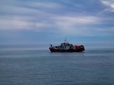 Sakin bir denizin ve bulutlu gökyüzünün arka planında çekilmiş bir gemi fotoğrafı.