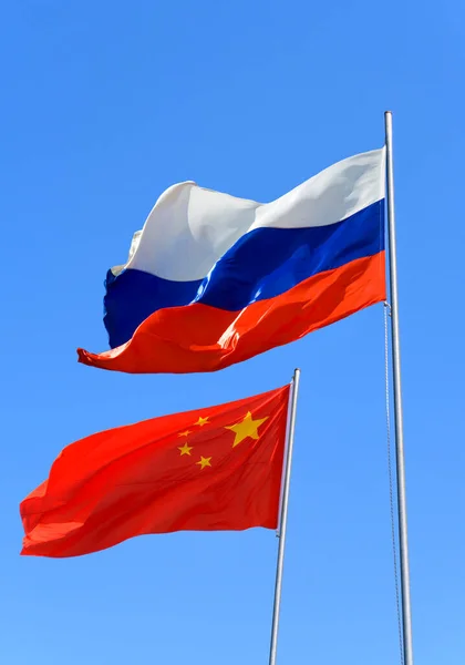 俄罗斯和中国的国旗迎着蓝天迎风飘扬 — 图库照片
