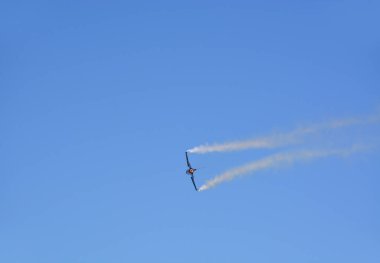 Mavi gökyüzünde bir askeri jet uçuyor.