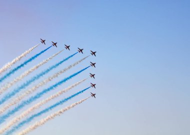 Mavi gökyüzünde bir askeri jet uçuyor.