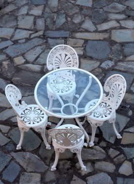 Yunanistan 'da taş bir terasta zarif beyaz masa ve sandalyeler duruyor