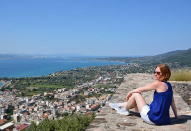 Nafpaktos, Yunanistan. Mayıs 2020: Kızıl saçlı bir kız ve Yunanistan 'daki tatil beldesi Nafpaktos' un manzarası