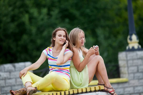 Girl on a bench with phones — Stock Photo, Image