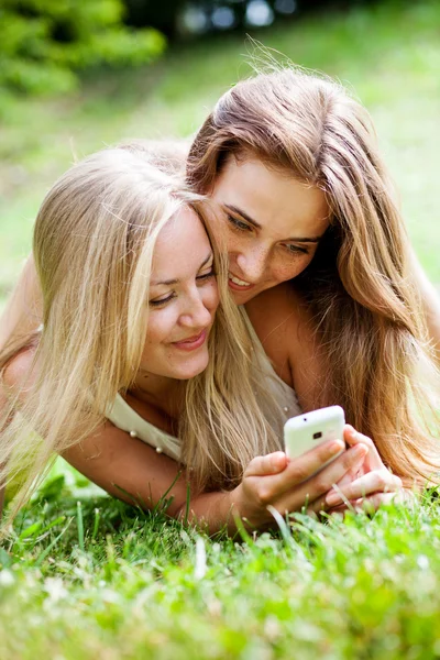 Flickan i parken med mobiltelefoner — Stockfoto