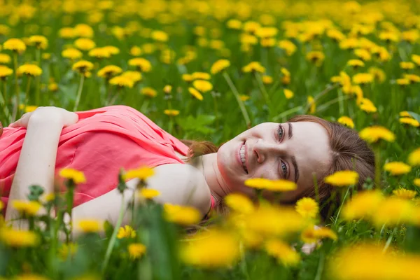 Schönes Mädchen liegt auf dem Feld von Löwenzahn — Stockfoto