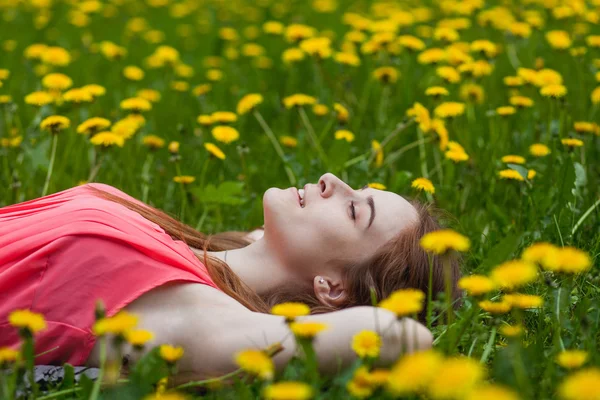 Bella ragazza sdraiata sul campo di denti di leone — Foto Stock