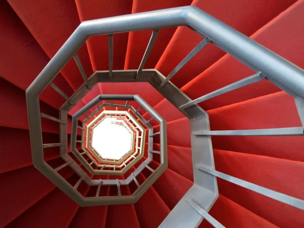 Spiral staircase of iron covered with a red carpet — Stock Photo, Image