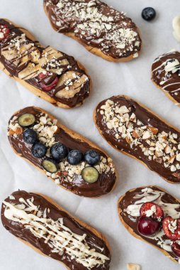 Çikolata soslu, fındıklı ve dutlu ekler. Lezzetli çikolata, fındık, muz, kiraz ve yaban mersinli ekler. Tabakta tatlı. Üst görünüm