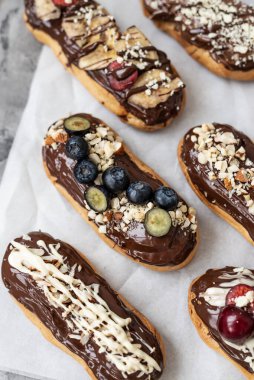 Çikolata soslu, fındıklı ve dutlu ekler. Lezzetli çikolata, fındık, muz, kiraz ve yaban mersinli ekler. Tabakta tatlı. Üst görünüm