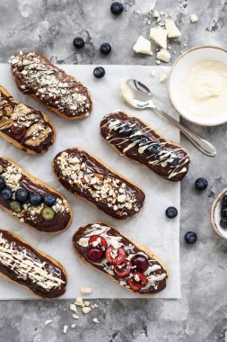 Çikolata soslu, fındıklı ve dutlu ekler. Lezzetli çikolata, fındık, muz, kiraz ve yaban mersinli ekler. Tabakta tatlı. Üst görünüm