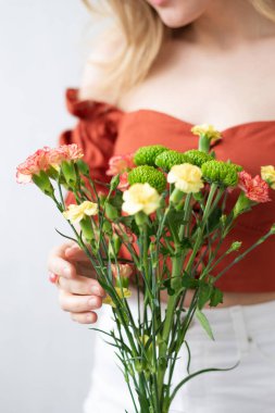 Kadın ellerinde bir buket çiçek. Cam vazoda güzel bir kasımpatı çiçeği buketi. Dekorasyon için taze kesilmiş çiçekler. Kompozisyonlar ve çiçek buketleri yapmak 