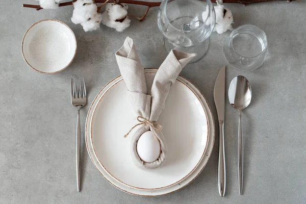 Table setting for Happy Easter day. Festive Easter table setting with Easter bunny made of linen napkin and egg. Stylish elegant Easter brunch table setting