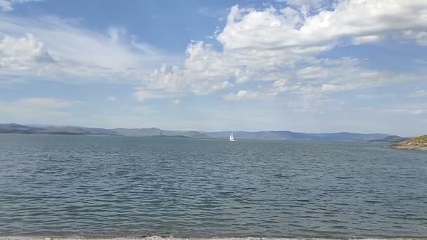 Clear Water Small Waves Mountains Distance Clouds Yacht Moving — Stockvideo
