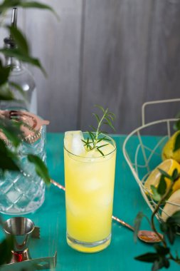 Armut Colins Kokteyli. İçi armut püresi kokteyli dolu viski bardağı ya da turkuaz masa yüzeyindeki malzemeler ve bar aletleriyle çevrili moktakolar içilmeye hazır..