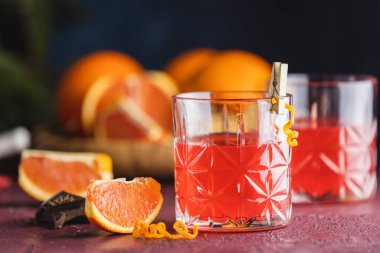 İki bardak çikolatalı kırmızı turuncu negroni, bir italyan kokteyli, bir aperatif, ilk kez 1919 'da Firenze, İtalya' da karıştırılmış, koyu kırmızı bordo masasındaki malzemelerin sunduğu alkollü acı kokteyl..