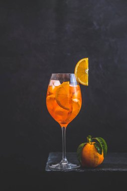 Kokteyl aperol spritz koyu arka plan üzerinde su damlaları ile büyük şarap cam. Portakal dilimleri ile yaz alkol kokteyli. İtalyan kokteyl aperol spritz kayrak tahtası üzerinde. Trendy içecek