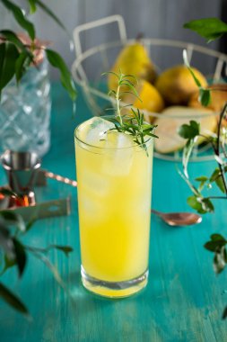 Armut Collins Kokteyli. Armut püresi kokteyli dolu viski bardağı ya da turkuaz masa yüzeyindeki malzemeler ve bar aletleriyle çevrili moktakolar.