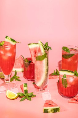 Different elegant glasses with watermelon cocktail. Splash, splatter, water drops on the pink background with sun light. Art food or drink concept.