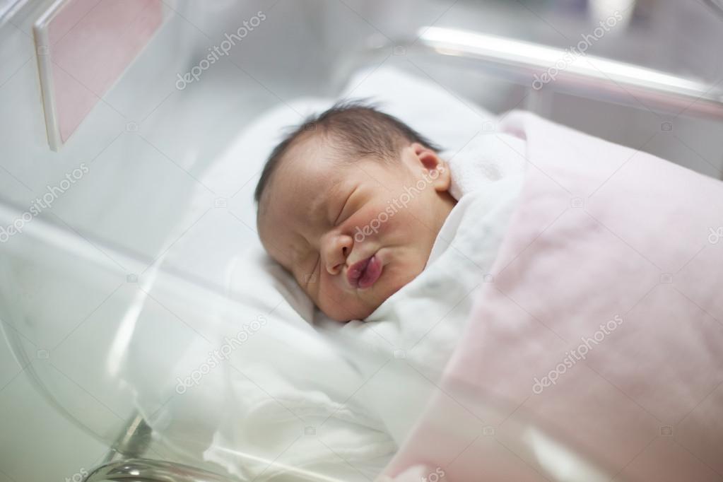 New born infant asleep in the blanket in delivery room