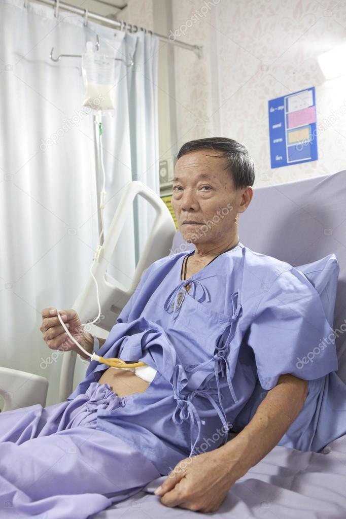 Old man patient feeding liquid food on hospital bed