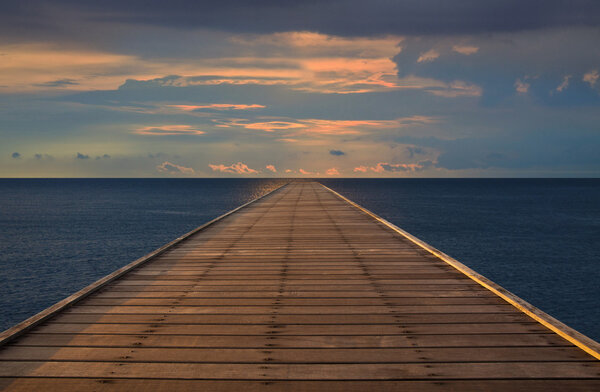 Old wood bridge to the sea with cloudy sky