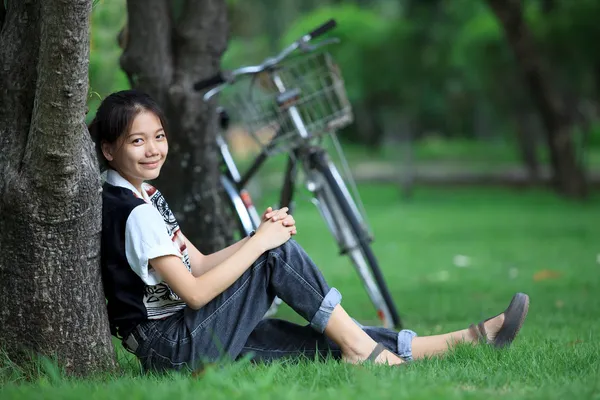 Frau sitzt mit Fahrrad im grünen Garten — Stockfoto