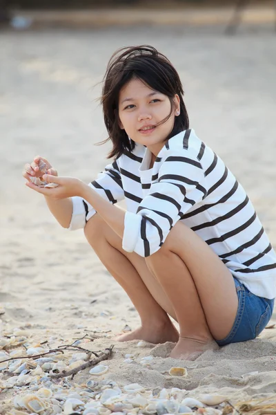 Tonåring kvinna sitter på stranden och havet skalet i handen — Stockfoto