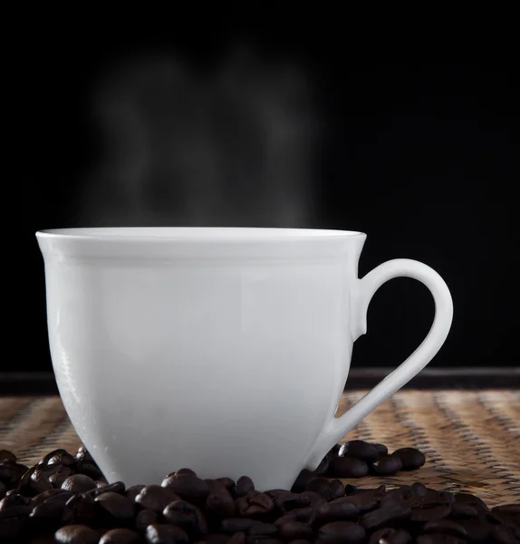 Weiße Tasse und Kaffeebohnen auf Holztisch geröstet — Stockfoto