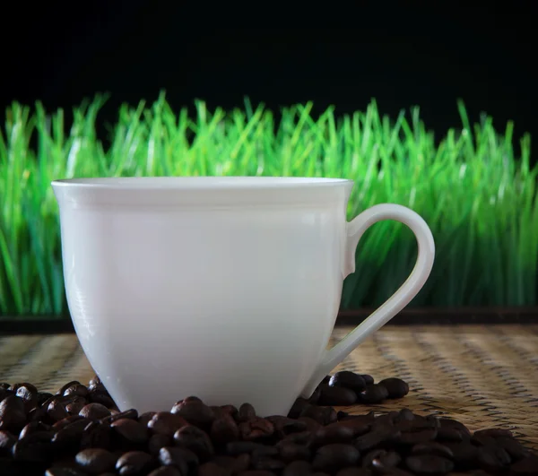 Witte kop en koffieboon geroosterde op houten tafel — Stockfoto