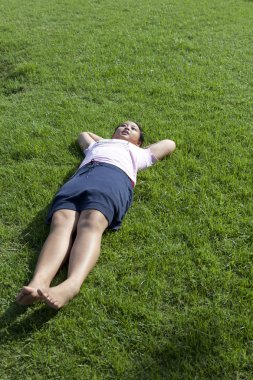 Parktaki çimlerde yatan kız.
