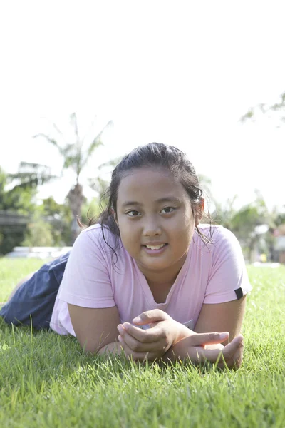 Mädchen liegt auf dem Gras im Park — Stockfoto