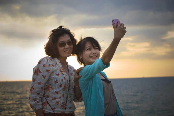 Dwóch azjatyckich kobiet są fotografowane na tle morza — Zdjęcie stockowe