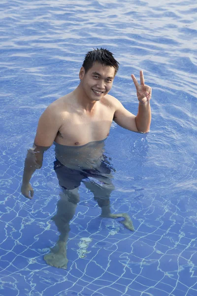Giovane asiatico uomo standing in clear acqua piscina e smiling — Foto Stock