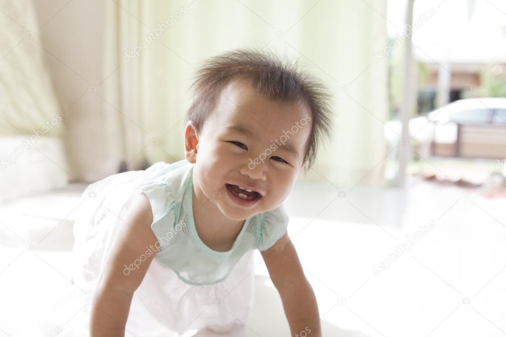 Face of asian baby 10 month aged crawling in living room