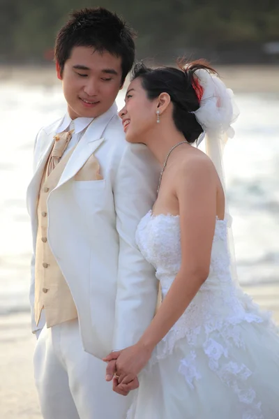 Couple of young man and woman in wedding suit standing beside sea beach — Stock Photo, Image
