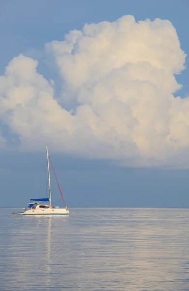 Beyaz Yatçılık gemi ve düz deniz mavi gökyüzü beyaz bulutlar — Stok fotoğraf