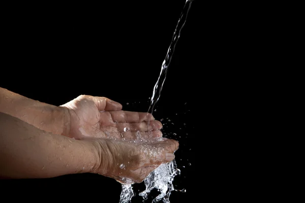 Hand and pouring water on black background — Stock Photo, Image
