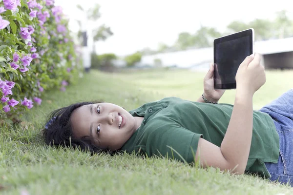 Flicka och tablett dator på grönt gräs — Stockfoto