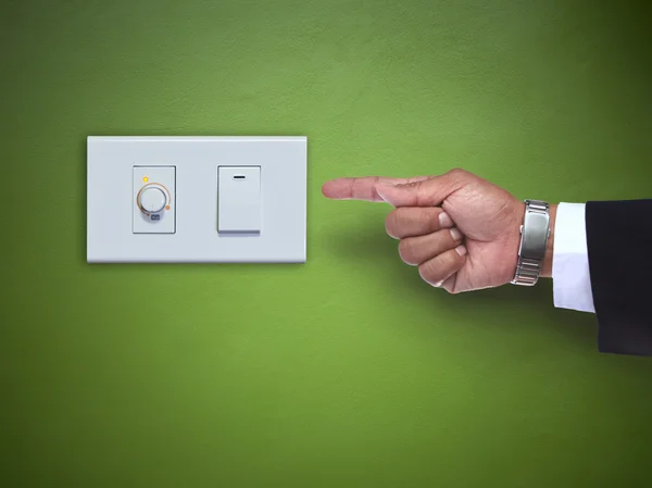 Hand wijzen om te schakelen ofelectric toestel op groene muur — Stockfoto