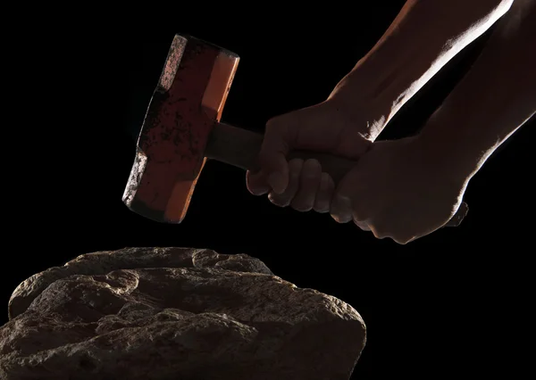 Hand und Hammer brechen auf dem Felsen isoliert auf schwarz — Stockfoto