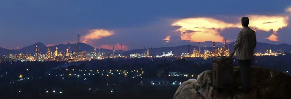 Investir avec un gros sac debout sur le rocher et regardant vers la ville de l'industrie — Photo