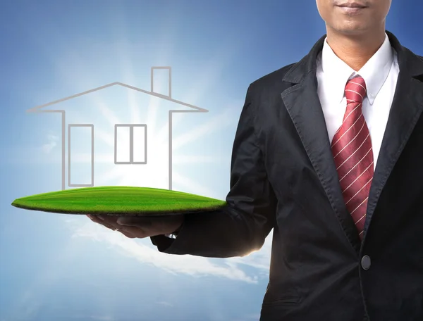 Business man holding new home on empty land for sale — Stock Photo, Image