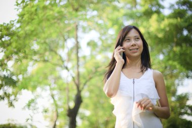Kadın iletişim teması için parkta cep telefonuyla konuşuyor