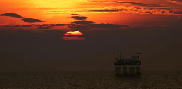 Hélicoptère atterrissant sur la plate-forme pétrolière avec belle scène de coucher de soleil — Photo